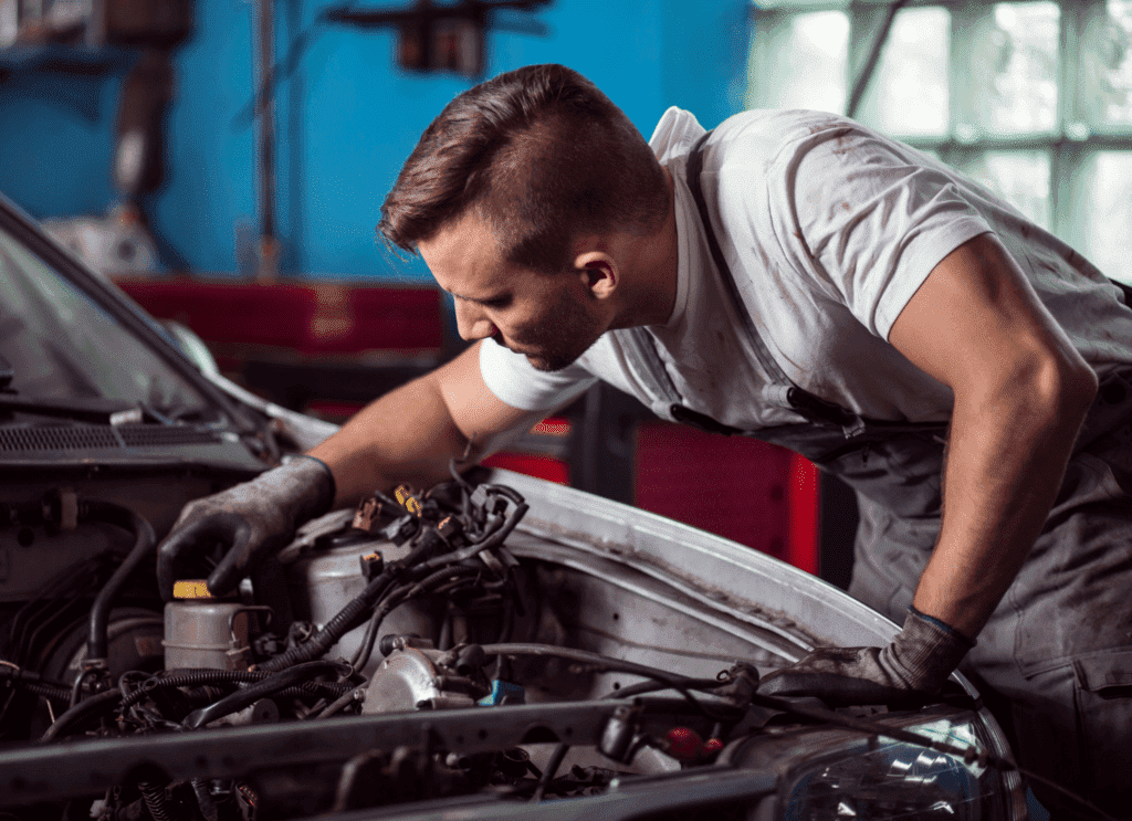 Mechanic inspecting vehicle engine components in a repair shop, emphasizing certified collision repair and quality service at Barry's Collision Repair.