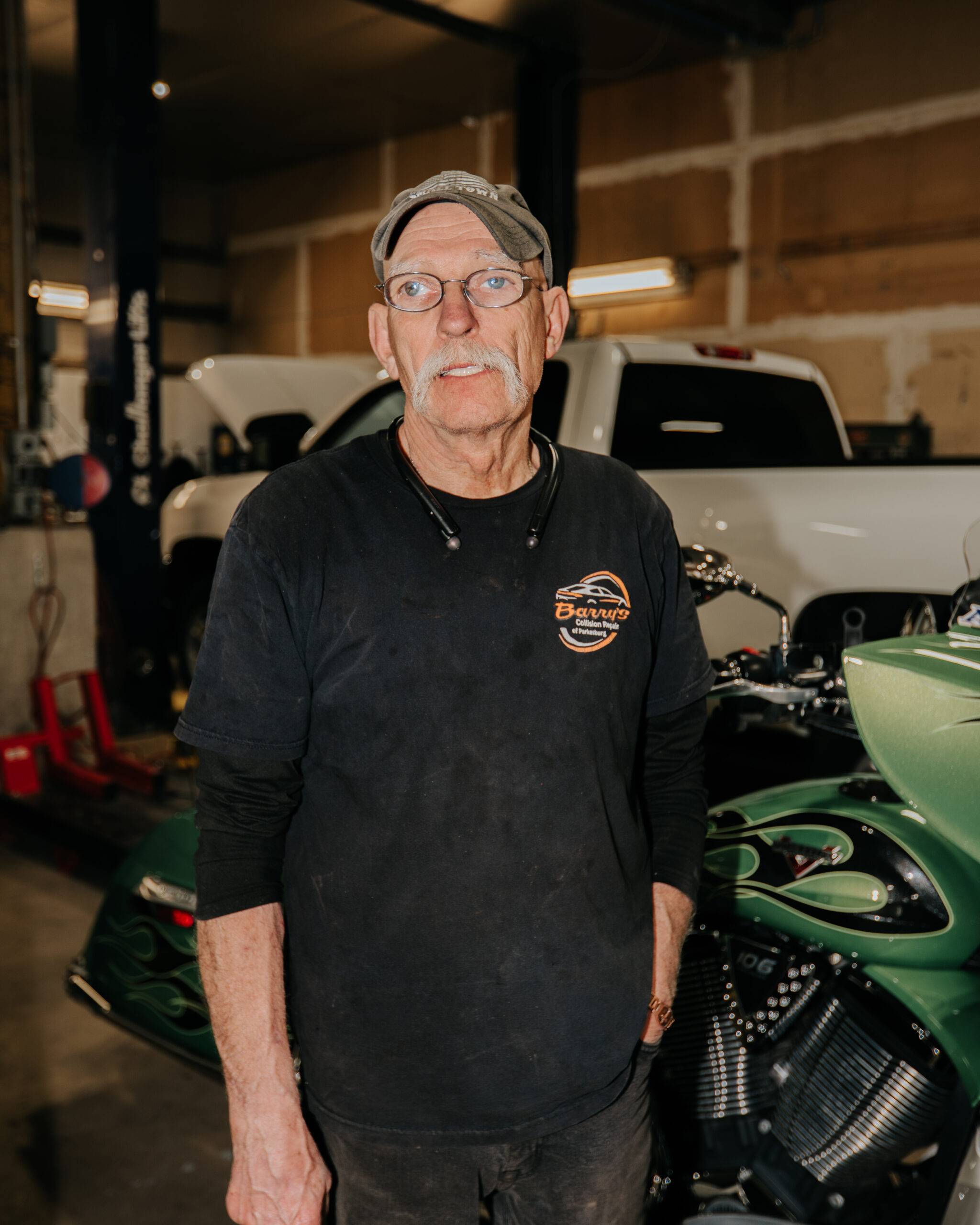 Barry's Collision Repair technician in shop with motorcycle and truck.