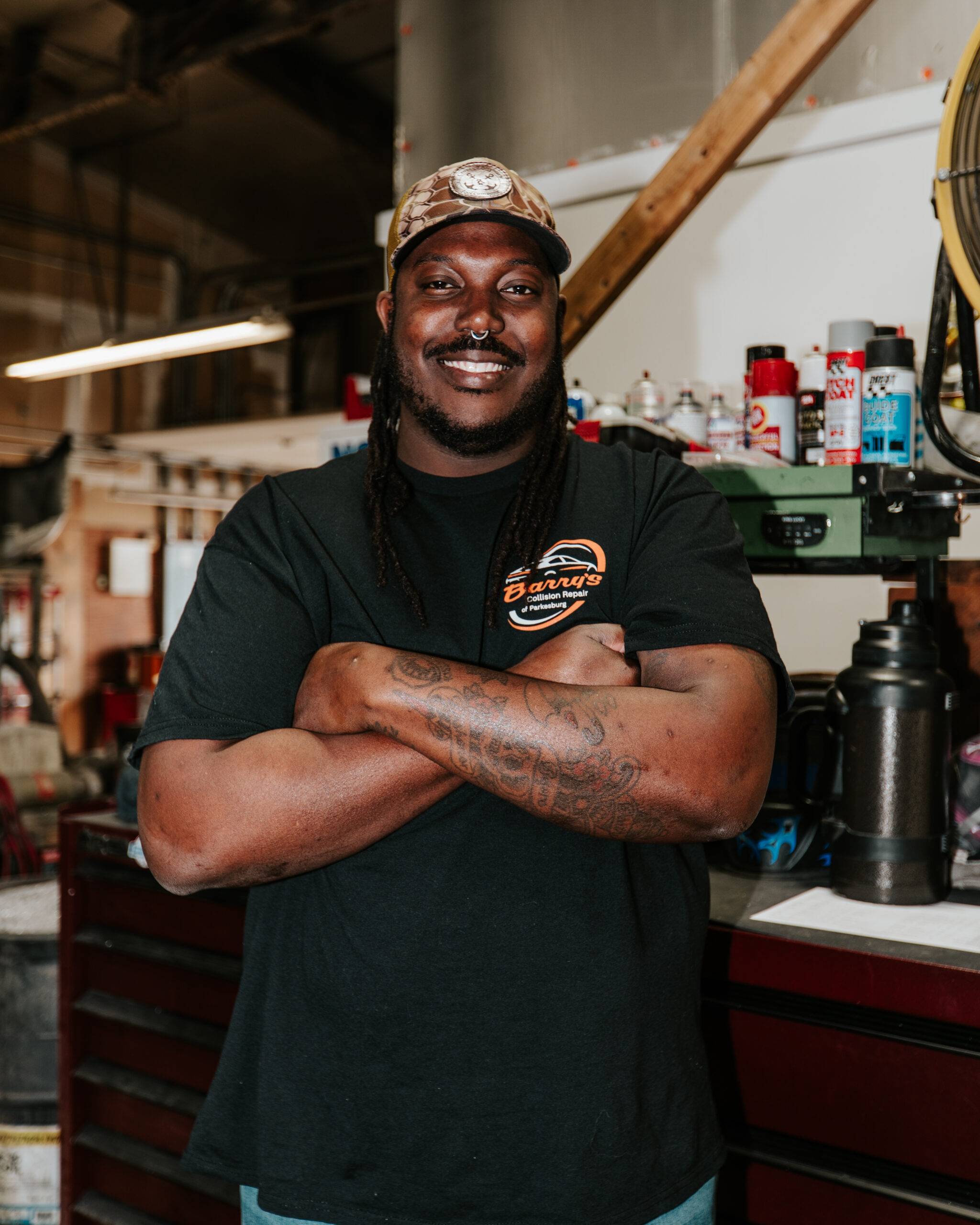 Barry's Collision Repair technician smiling in auto shop, showcasing skilled team members.