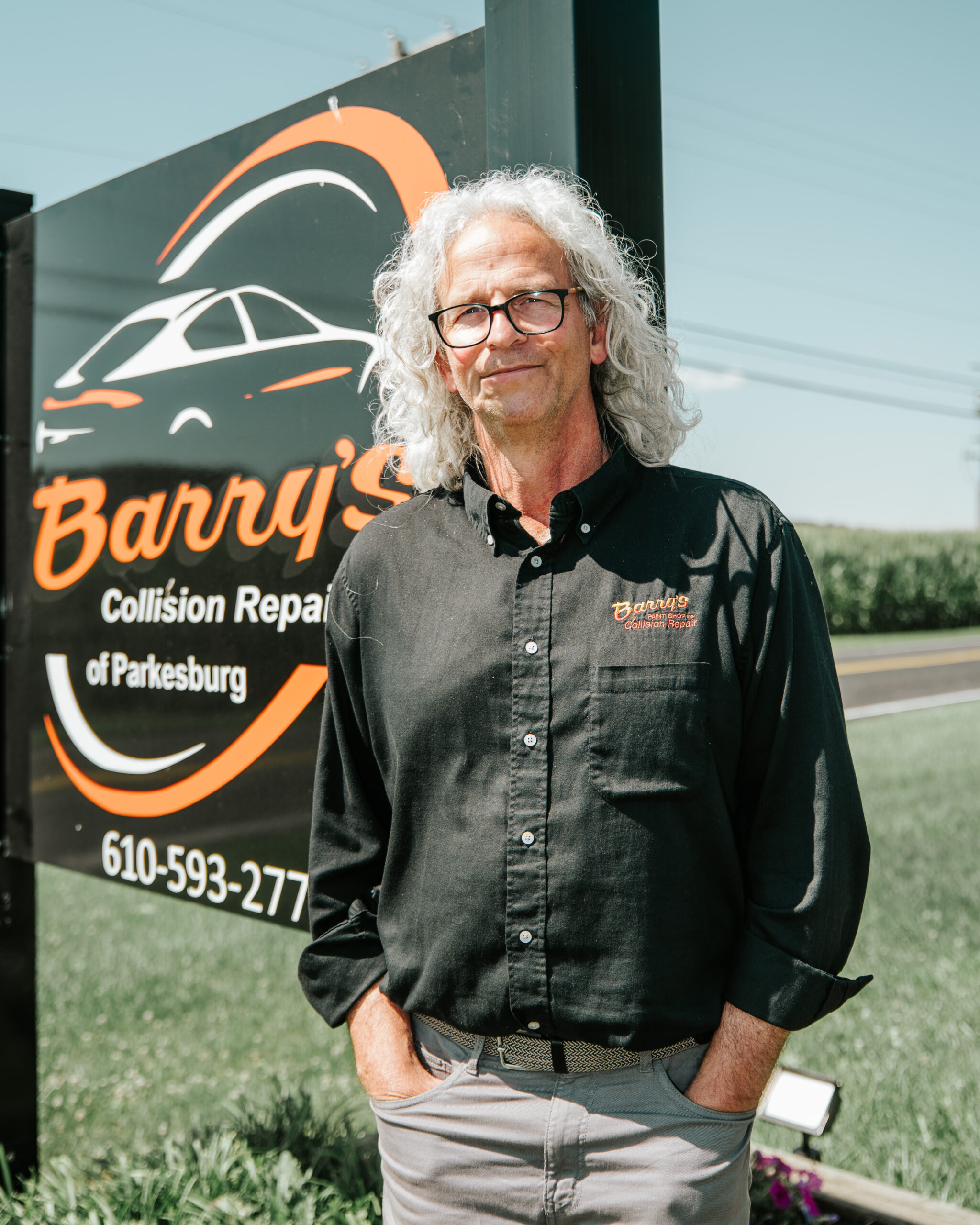 Barry's Collision Repair team member standing in front of shop sign, Parkesburg Pennsylvania.